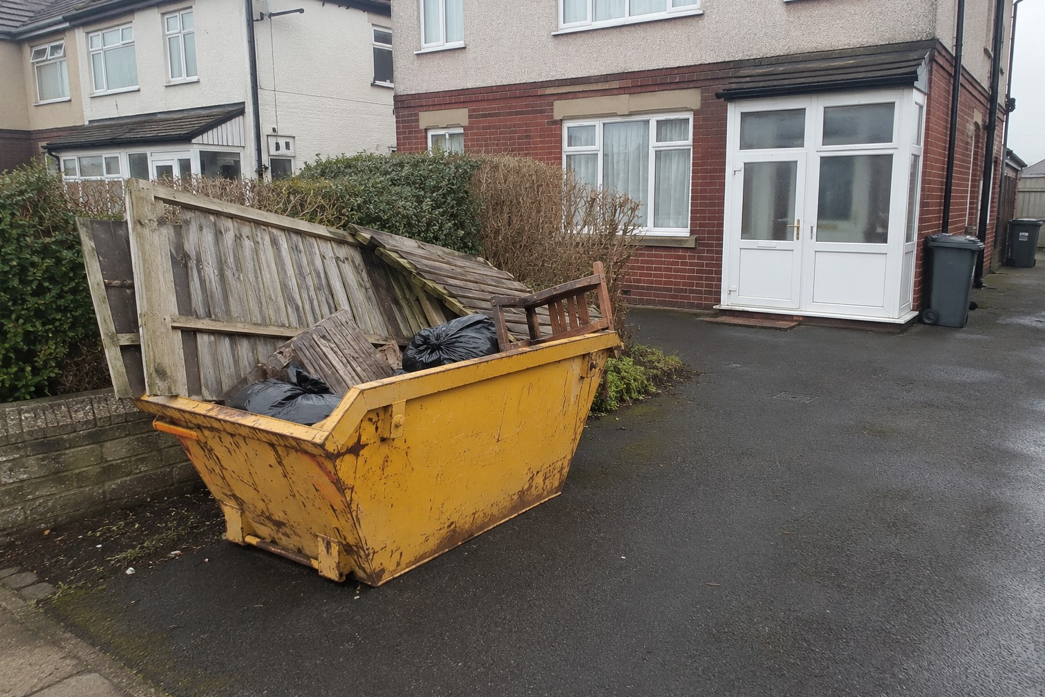 Yellow 4-yard skip on a residential driveway in Scarborough, part-filled with old fence panels and garden waste
